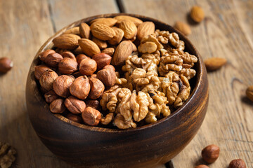 Set nuts in wooden bowl on wooden table close up
