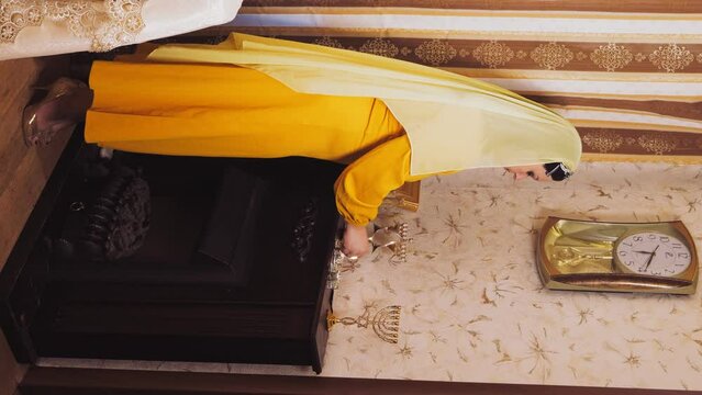 A Jewish woman in a wig and a head covering lights candles on the eve of Pesach, which coincides with Saturday. vertical video