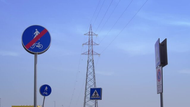 Traliccio dell'elettricit&agrave; circondato da segnali stradali sotto un cielo azzurro