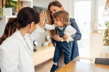 Female pediatrician at the home visit, giving a high five to tod