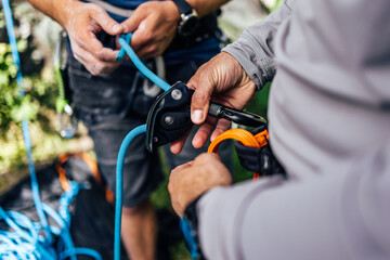 Two males holding a hook and rope, doing the security part before climbing.