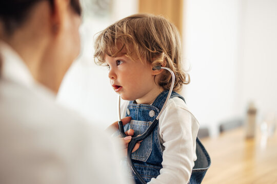 Photo of a calm toddler, using doctors' accessories, enjoying hi