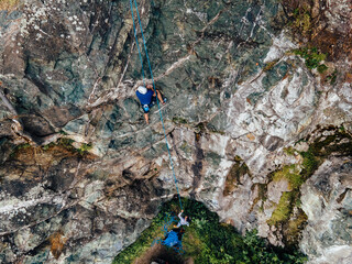 Obraz premium Top view of a man being security to his climber friend, reaching the top.
