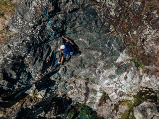 Obraz premium Top view of an adult man with a hamlet, climbing on the rock.
