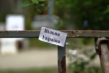 Krakow, Poland - May 1 2022: Small piece of paper with slogan FREE UKRAINE in Ukrainian language put on fence in public park in Krakow, Poland