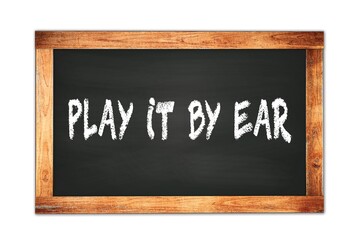 Fototapeta premium PLAY IT BY EAR text written on wooden frame school blackboard.