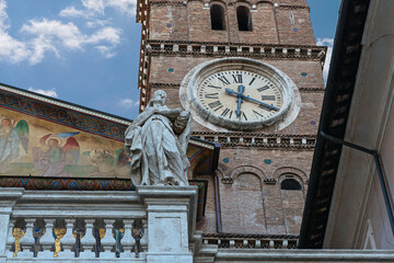 a fragment of the facade of a Roman cathedral with a beautiful tower clock and a statue of a saint...