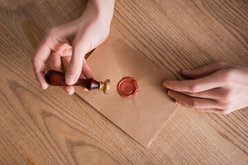 partial view of lawyer holding stamper near craft paper envelope sealed with wax.