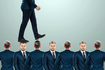 A man in a suit steps over the heads of employees. The concept of career growth, promotion,...