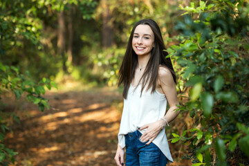 A beautiful happy teenage brunette girl outdoors in a wooded area in the spring - Powered by Adobe