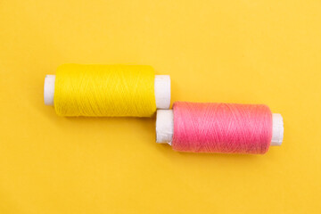 yellow or pink color yarn or spool thread over on yellow background