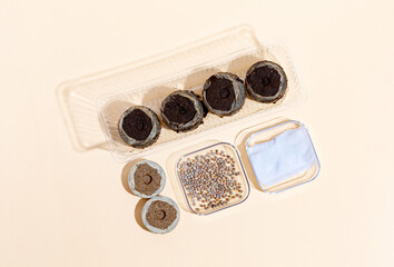 Round Peat briquettes for growing seedlings dry, wet on a beige background and radish seeds in container. Isometric.