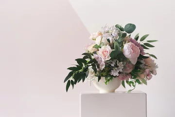 Foto op Plexiglas A composition of different flowers in a white vase on a square podium. The concept of a flower shop. A beautiful freshly cut bouquet. Flower delivery. High quality photo © daryakomarova