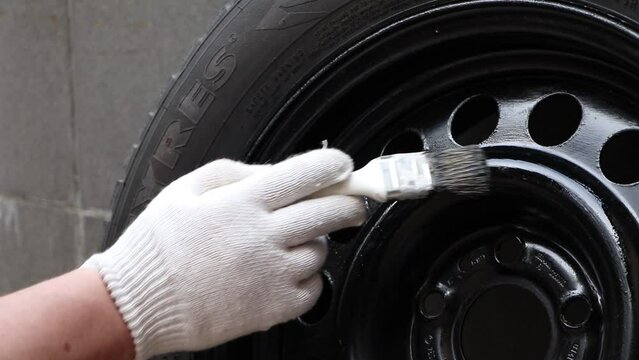 Painting a car disc. Restoration of a disk for a car. Used winter studded tire for car.Studded wheel for car close-up. 