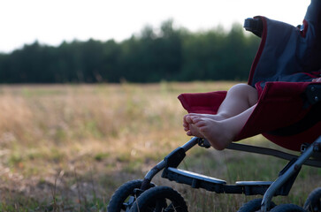 Little baby sleeping in the summer in a pram outdoors against the background of the landscape