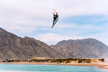 Kiteboarder jumping high near Bedouins village in Blue Lagoon, Sinai, Egypt