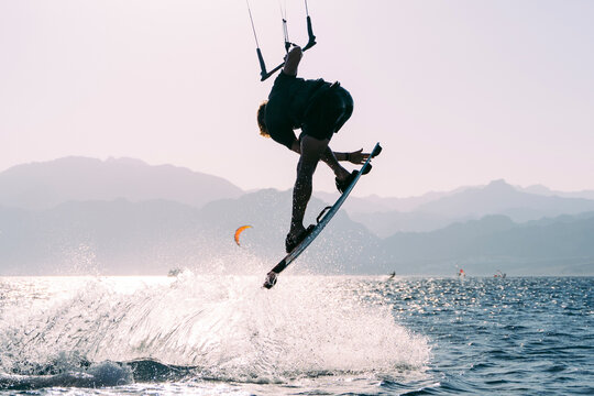 Kiteboarder grabing board after jump with water splashes, Dahab, Egypt