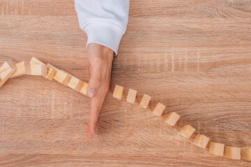 hand stops falling dominoes or wooden puzzle