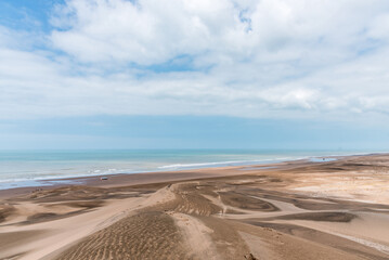 Panoramic photo of the sandy dunes of a desert in front of the sea