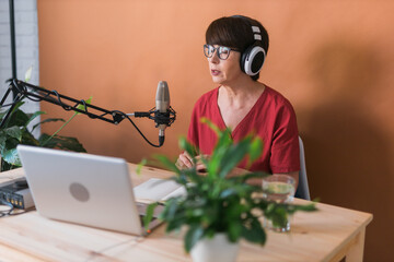 Middle-aged female radio presenter talking into the microphone and reading news - radio broadcast...