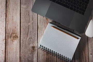 Workspace with laptop, notebook and pencil on wooden background. Top view. Copy space. Selective focus.
