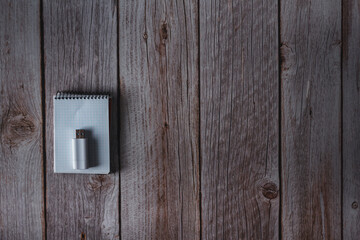 Small notebook and USB flash drive on wooden background. Top view. Copy space. Selective focus.