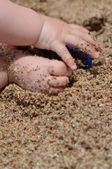 Hands of a small child in the sand with toys