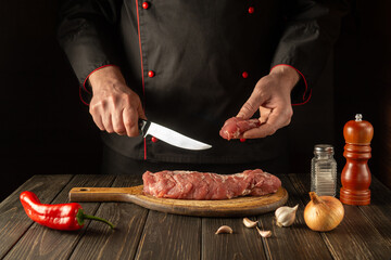 The chef cuts beef raw meat on a cutting board before barbecue. Asian cuisine. Preparing a delicious meal in the kitchen