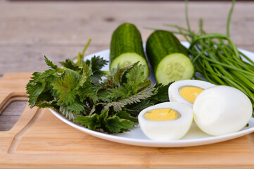 Diet salad with cucumber, green onion, boiled eggs and nettle leaves. Spring vitamin salad.