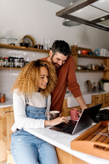 Couple looking at laptop in kitchen. - 502469870