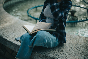 Manos de mujer pasando paginas de un libro sentada en un parque. Concepto de Estilo de Vida.