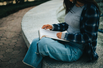 Fototapeta na wymiar Manos de mujer pasando paginas de un libro sentada en un parque. Concepto de Estilo de Vida.