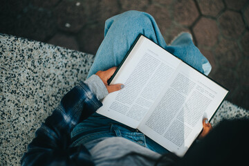 Manos de mujer pasando paginas de un libro sentada en un parque. Concepto de Estilo de Vida.