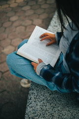 Manos de mujer pasando paginas de un libro sentada en un parque. Concepto de Estilo de Vida.