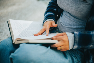 Manos de mujer pasando paginas de un libro sentada en un parque. Concepto de Estilo de Vida.