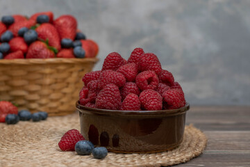 Strawberry and blueberry in basket and raspberries in bowl on wood table. Fresh berries.