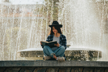 mujer sentada al costado de una pileta leyendo un libro. Concepto de personas y estilos de vida.