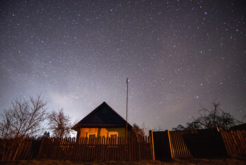 Fototapeta na wymiar An old wooden village house on the background of the night starry sky in the countryside (country, village) in spring at night