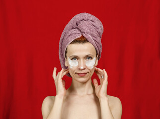 Smiling half naked woman with a towel on her head. Hands near the head. Cosmetic patches under the...