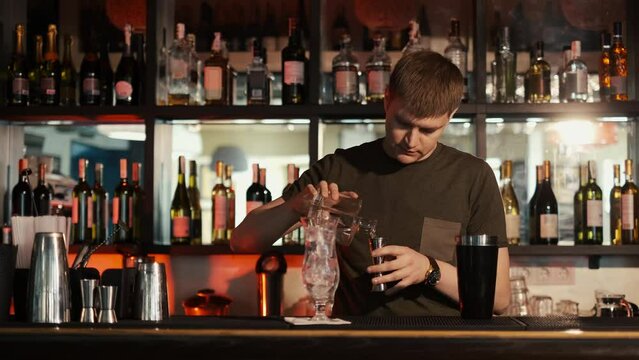 A professional bartender is preparing an alcoholic cocktail with ice cubes to customers at the bar or disco club,Sex on the beach cocktail.