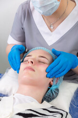 Naklejka premium A female cosmetologist manually treats the patient's skin with a moisturizing and toning gel.