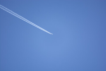 white streaks behind the jet in the blue sky