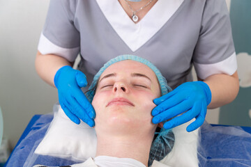 Naklejka premium A female cosmetologist manually treats the patient's skin with a moisturizing and toning gel.