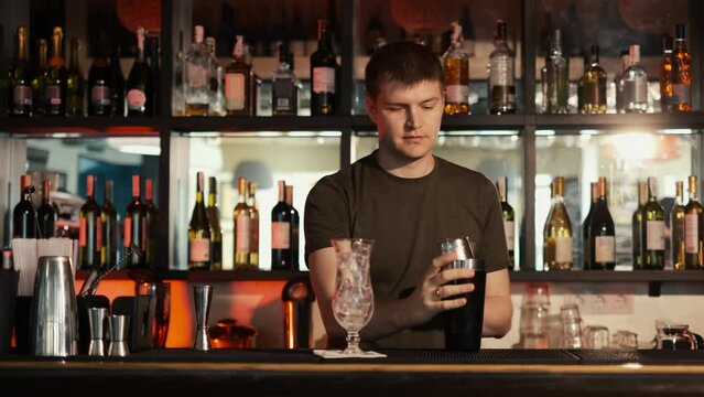 A professional bartender is preparing an alcoholic cocktail with ice cubes to customers at the bar or disco club,Sex on the beach cocktail.