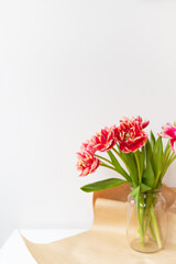 A beautiful spring bouquet of tulips stands in a vase. Surprise concept, birthday. Vertical photo, place for an inscription.