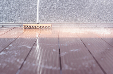 Close-up of a scrubber on a terrace during cleaning with splashing water and soapy water