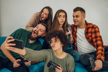 Friends having fun at home and taking selfie with a smartphone