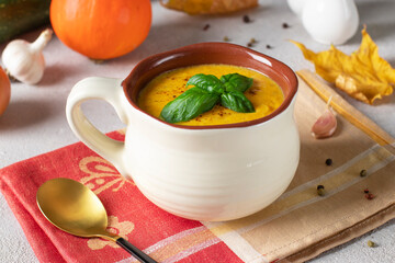 Creamy pumpkin and zucchini soup in a cup on gray background