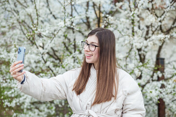 Young adult girl communicates via video chat using mobile device. Spring season.