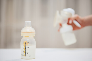 manual breast pump on background of hand with bottle with milk
